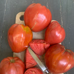 Load image into Gallery viewer, Tomatoes on a cutting board with a knife
